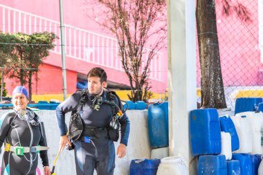 Farklı yaşlarda iki dalgıç havuzun dışında dikiliyor.