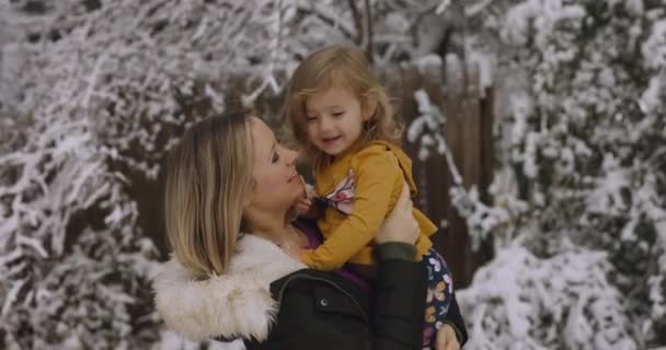 Młoda kobieta bawi się ze swoją córeczką w snowparku w Santa cap 4k Filmik Stockowy