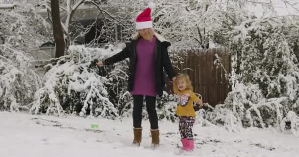 Młoda kobieta bawi się ze swoją córeczką w snowparku w Santa cap 4k Wideo Stockowe bez tantiem