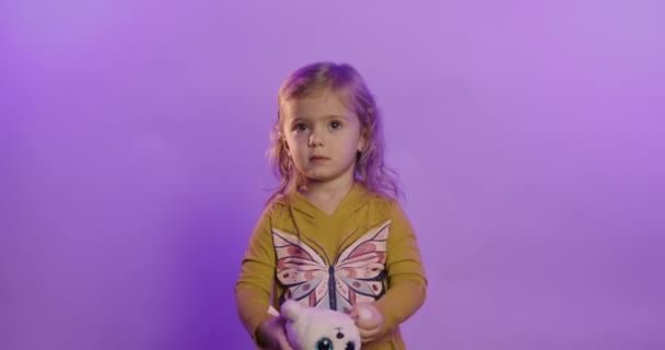 Портрет взволнованной маленькой девочки, изолированной на фиолетовом фоне студии смеяться над смешной шуткой, радоваться счастливый маленький ребенок весело, детский юмор, развлекательная концепция Стоковое Видео