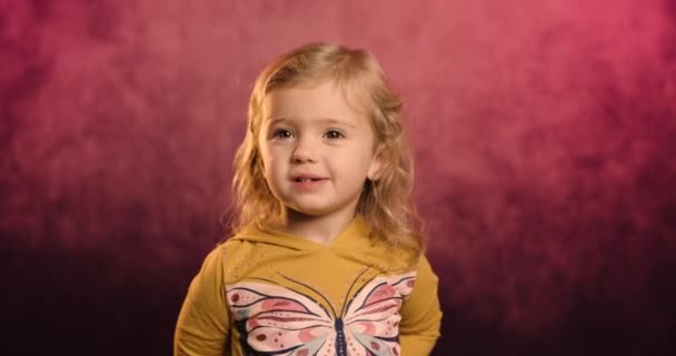 Heyecanlı küçük bir kızın portresi şarap rengi bir stüdyonun arka planında izole edilmiş çilek kokusu komik şakalara kahkahalar, aşırı neşeli küçük çocuk eğlencesi, çocuk mizahı, eğlence konsepti — Stok video