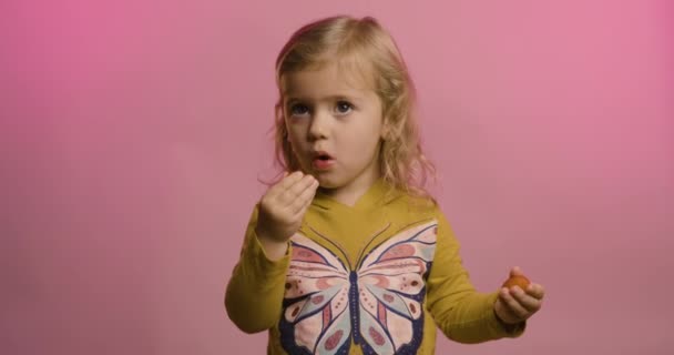 Portret podekscytowanej dziewczynki jedzącej truskawki odizolowane na różowym tle studia śmieją się z zabawnego żartu, rozradowane szczęśliwe małe dziecko bawi się, dziecięcy humor, koncepcja rozrywki Wideo Stockowe bez tantiem