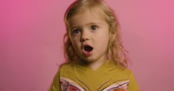 Портрет возбужденной маленькой девочки едят клубнику изолированы на розовом фоне студии смеяться над смешной шуткой, радоваться счастливый маленький ребенок весело, детский юмор, развлекательная концепция Видеоклип
