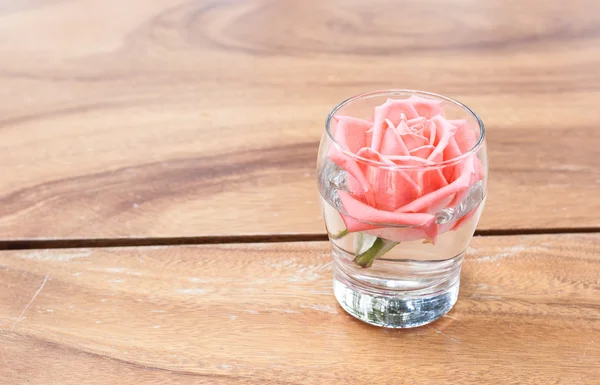 Rose in einem Glas schmücken auf dem Tisch. — Stockfoto