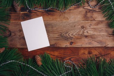 Taze yeşil çam dalları ve ahşap arka planda köknar kozalakları, üst manzara, kopyalama alanı. Noel çerçeveli arka plan, yeni yıl kartı şablonu, maket