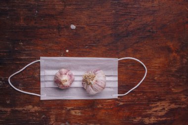 Gazlı bez maskeli iki sarımsak ampulü. Grip, covid 19, iltihap önleme. Doğal antioksidan piquant sebze. Üst görünüm, alanı kopyala