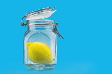 İçinde limon olan cam kavanoz, mavi arka planda.