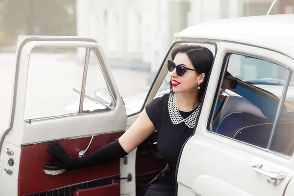 young woman in black sunglasses driving a retro car, sunny summer day
