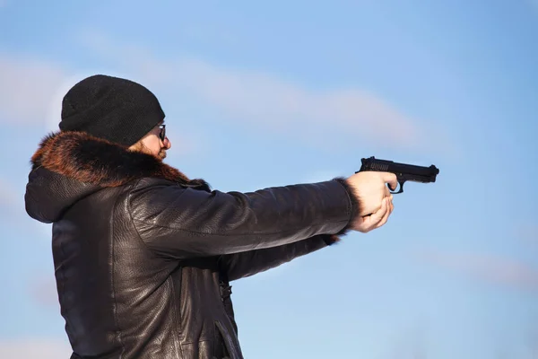 Avrupa görünümlü bir adam kış ormanında hava tabancasıyla ateş eder.