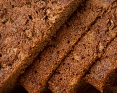 Dilimlenmiş çavdar ekmeği ve kimyon, tahtanın üzerinde yatıyor.