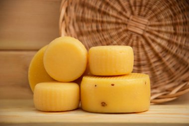 Hasır sepetli, keten peçeteli, sağlıklı besinli, doğal ahşap arka planda çeşitli peynir kafalar.