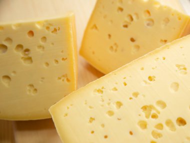 Doğal ahşap arka planda farklı çeşitlerde peynir, bütün ve dilimlenmiş.