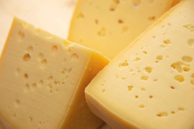 Doğal ahşap arka planda farklı çeşitlerde peynir, bütün ve dilimlenmiş.