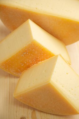 Doğal ahşap arka planda farklı çeşitlerde peynir, bütün ve dilimlenmiş.