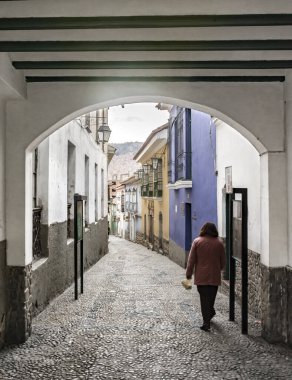 LA PAZ, BOLIVIA - 14 Ocak 2018: Kimliği belirsiz bir kadın, La Paz, Bolivya 'da renkli binaları olan, Jaen caddesi boyunca yürüyor..