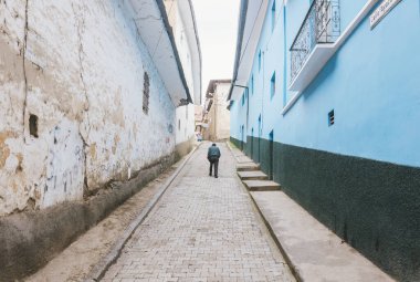 Sorata, Bolivya - 29 Ocak 2018: Kimliği belirsiz yaşlı bir adam, Bolivya 'nın sömürge şehri Sorata' nın arka planında dağlarla yürür..