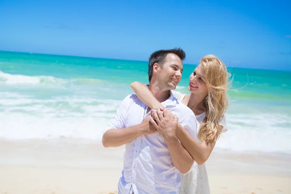 Couple joyeux embrassant et posant sur la plage par une journée ensoleillée — Photo