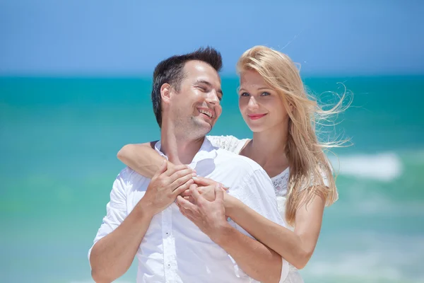 Pareja alegre abrazando y posando en la playa en un día soleado — Foto de Stock