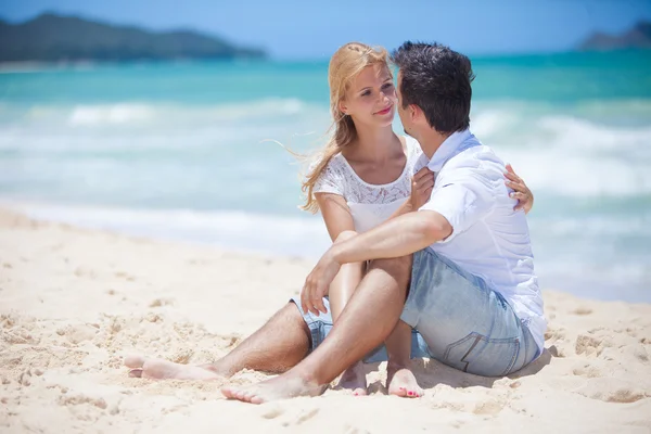 Casal alegre abraçando e posando na praia em um dia ensolarado — Fotografia de Stock