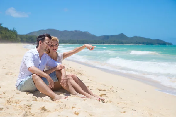 Χαρούμενο ζευγάρι αγκαλιάζει και να θέτουν στην παραλία μια ηλιόλουστη ημέρα — Φωτογραφία Αρχείου
