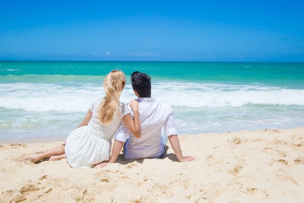 Casal alegre abraçando e posando na praia em um dia ensolarado — Fotografia de Stock