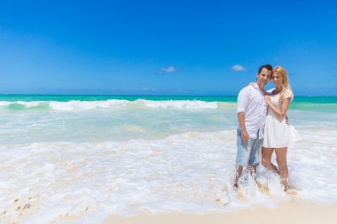 Çift kucaklayan ve güneşli bir günde sahilde poz