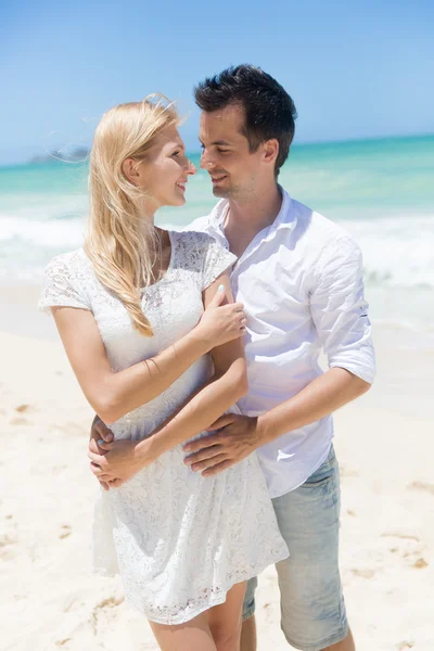 Pareja alegre abrazando y posando en la playa en un día soleado — Foto de Stock