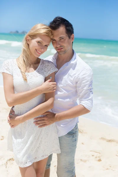 Fröhliches Paar, das sich an einem sonnigen Tag am Strand umarmt und posiert — Stockfoto