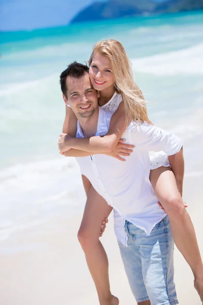 Happy young couple enjoying a solitary beach backriding — Stock Photo, Image