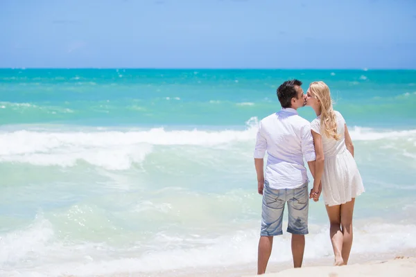 Fröhliches Paar, das sich an einem sonnigen Tag am Strand umarmt und posiert — Stockfoto