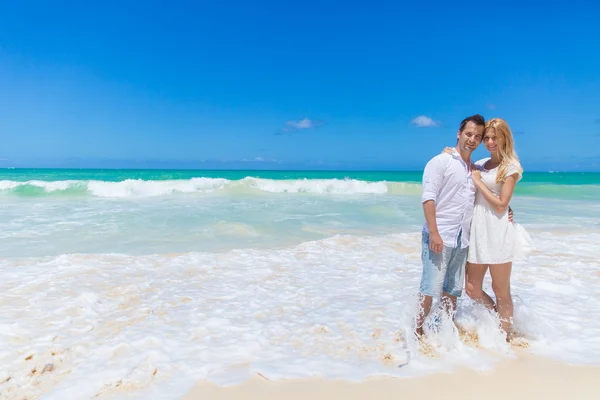 Casal alegre abraçando e posando na praia em um dia ensolarado — Fotografia de Stock