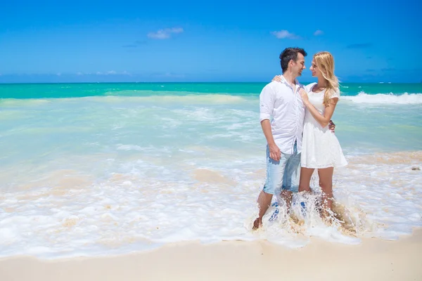 Casal alegre abraçando e posando na praia em um dia ensolarado — Fotografia de Stock