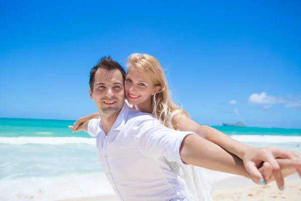 Cheerful couple having fun at the beach on a sunny day — Stock Photo, Image