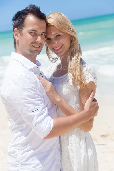 Cheerful couple embracing and posing on the beach on a sunny day — Stock Photo, Image