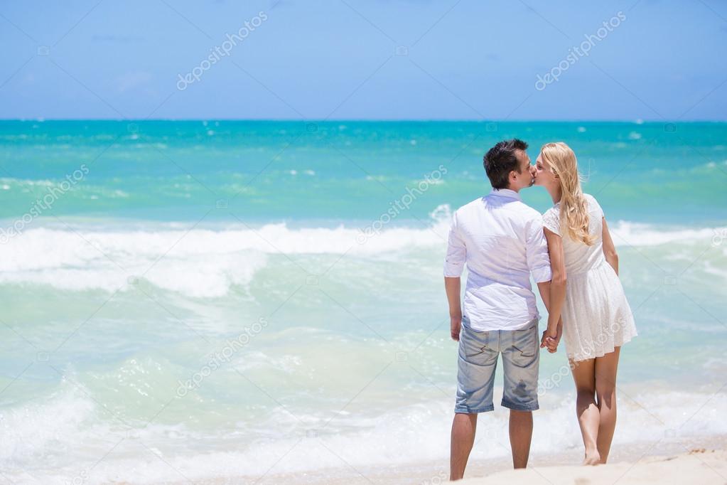 Cheerful couple embracing and posing on the beach on a sunny day