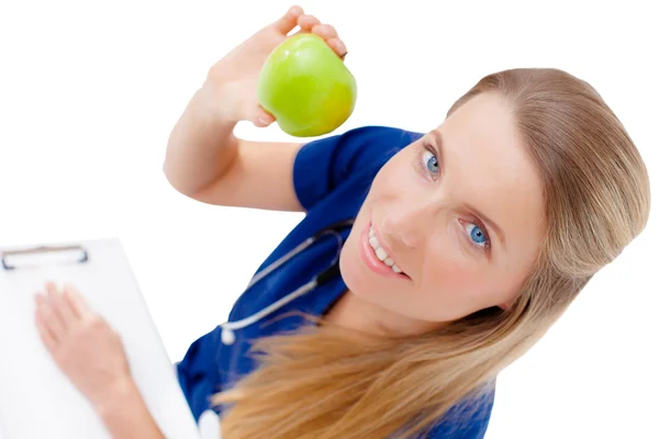 Smiling nurse or young female doctor giving an green apple. — Stockfoto