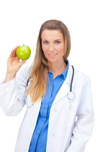 Smiling nurse or young female doctor giving an green apple. Royalty Free Stock Photos