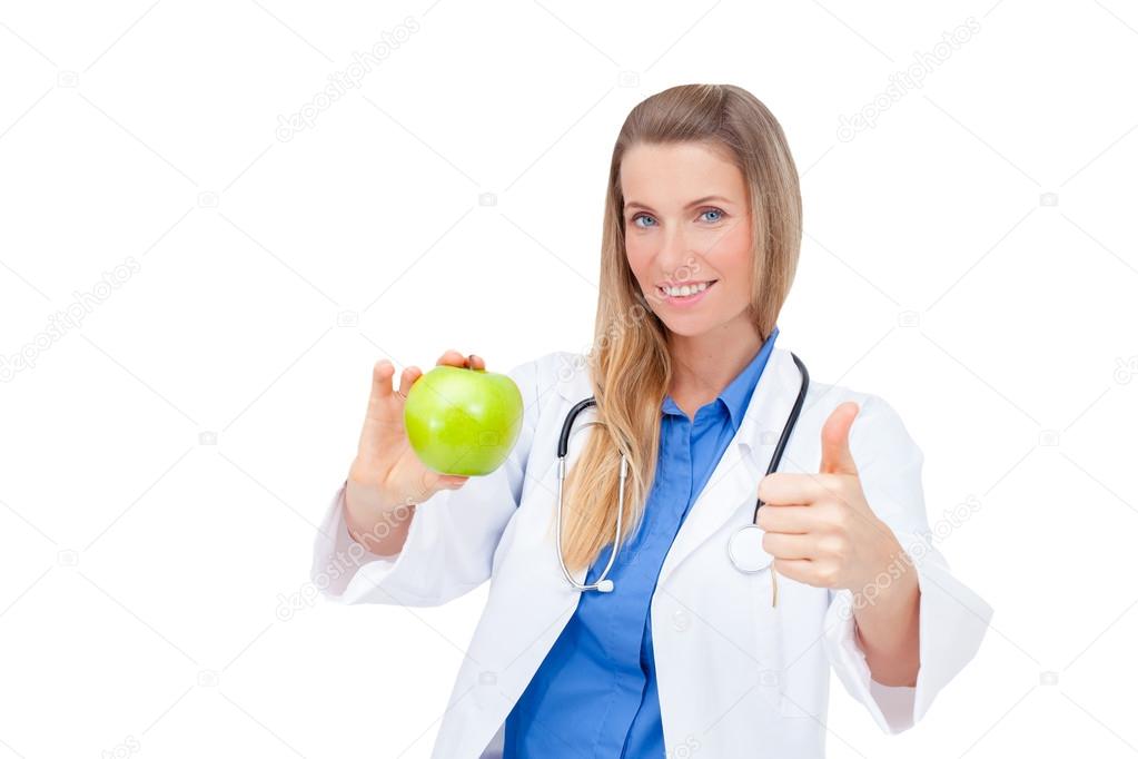 Smiling nurse or young female doctor giving an green apple.