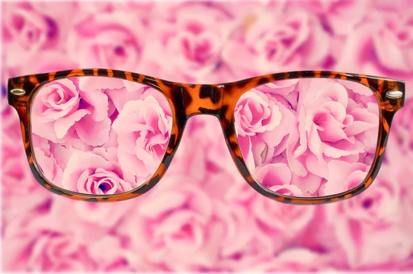 Brown glasses  on pink rose background — Stock Photo, Image