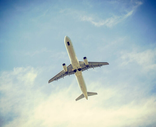 White airplane in blue sky in retro filter