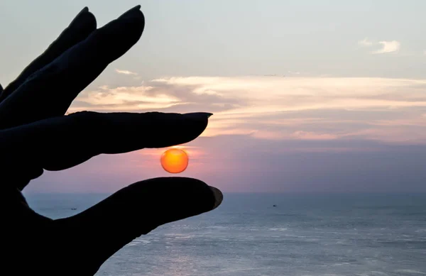 日落时分手握太阳在海面上的轮廓照片 — 图库照片