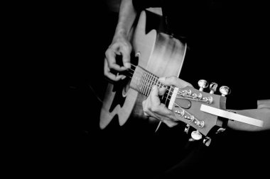 Siyah beyaz filtreyle akustik gitar çalan adamın parmaklarını kapat.