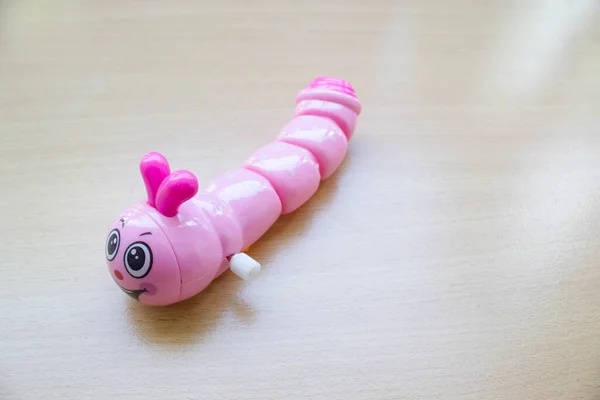 木制背景粉红线虫玩具 — 图库照片