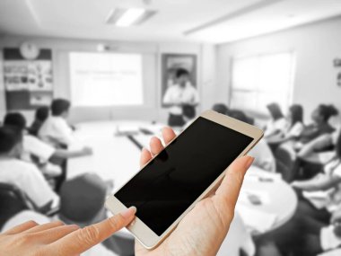 Kadın eli, toplantı odasındaki iş adamlarının bulanık fotoğrafında akıllı telefonu kapatır.