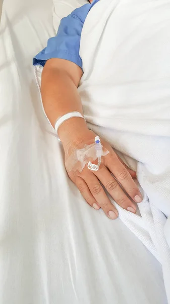 病院のベッドに横になっている患者の手による生理食塩水の準備の終わり — ストック写真