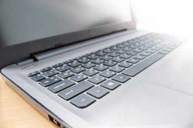 Ahşap masada yumuşak güneş ışığı olan bir dizüstü bilgisayar.