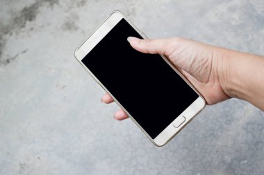 Kirli beton zeminde akıllı bir telefonu tutarken