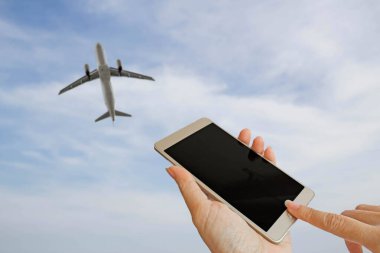 Mavi gökyüzü ve beyaz bulut arkaplanının bulanık fotoğrafında akıllı telefon kullan