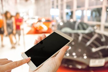 Motor fuarındaki ziyaretçilerin bulanık fotoğrafında el yapımı akıllı telefon kullan