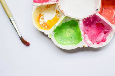 Renkli ve dağınık renk paleti ve beyaz arkaplanda boya fırçası